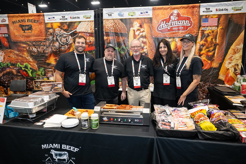Miami Beef team posing at their exhibit at Annual Meat Conference
